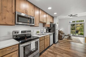 A modern kitchen with wooden cabinets, stainless steel appliances, and a view to the outdoors. - Quaint Riverfront Property Close to the Resort! Pet Friendly. (Steamboat Springs)
