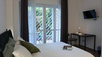 Ein Schlafzimmer mit einem Bett, einem Schreibtisch, einem Stuhl, einem Fernseher und einem Fenster mit Vorhängen.