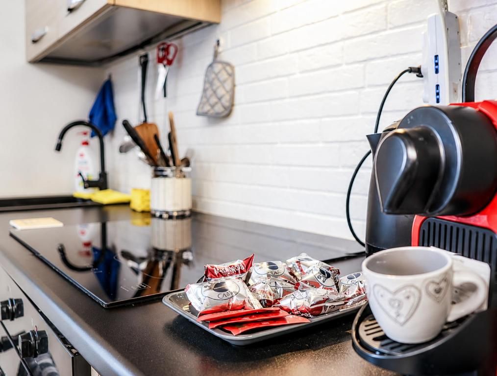 Eine Küche mit einer Kaffeemaschine, einer Platte verpackter Speisen und einer herzförmigen Tasse auf der Arbeitsfläche.