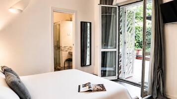 Ein Hotelzimmer mit einem Bett, einer Tür zu einem Badezimmer und einer Schiebetür zu einem Außenbereich.