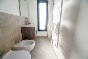 Ein Badezimmer mit einer Bidet-Funktion, einem Waschbecken und einem Spiegel.