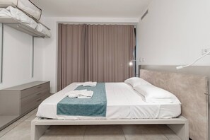 Una camera d'albergo moderna con un letto, un comodino, un armadio e una finestra con tende.