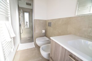 Un bagno con doccia, WC e lavandino.