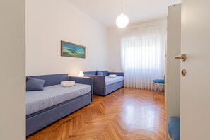 Ein Zimmer mit zwei blauen Sofas, einem Gemälde an der Wand, einem Holzboden und einer Tür mit Schlüsselloch.