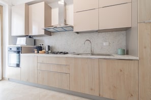 Eine moderne Küche mit hellen Holzschränken, einer Edelstahlspüle und einem eingebauten Backofen.