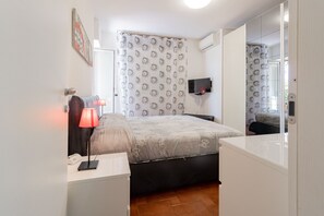 A hotel room with a bed, bedside table, lamp, and a TV mounted on the wall. - CASA CHRISTINE - Riva Ligure (Riva Ligure)