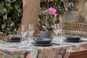 A table set for dining with clear glassware and black bowls, surrounded by greenery and a tree. - CASA CHRISTINE - Riva Ligure (Riva Ligure)