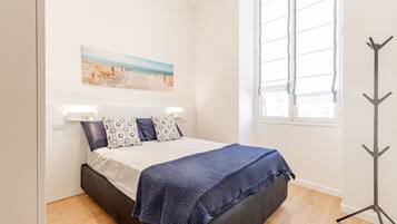 Un dormitorio con cama, ventana y perchero.