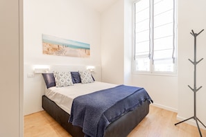 Ein Schlafzimmer mit Bett, Fenster und Kleiderständer.