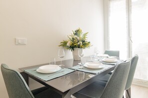 A dining table set with plates, glasses, and a vase of flowers. - ACQUAMARINA - Centro (Sanremo)