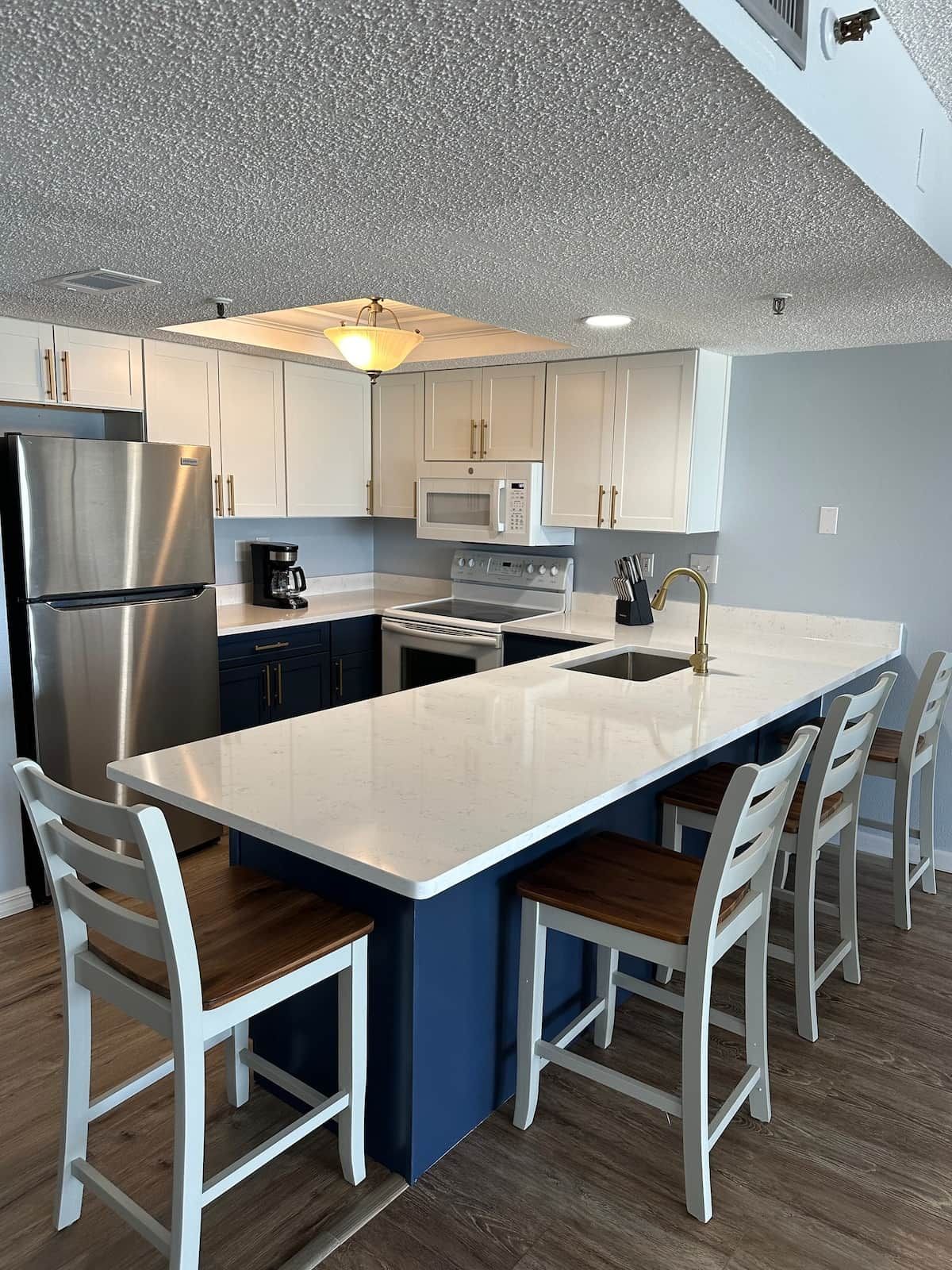 A modern kitchen with a central island, stainless steel appliances, and white cabinetry.