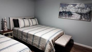 A bedroom with a bed, a bench, a nightstand, and a painting on the wall.