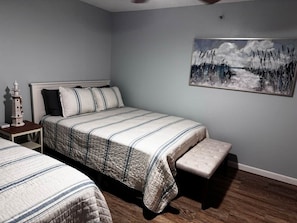 Un dormitorio con una cama, un banco, una mesita de noche y un cuadro en la pared.