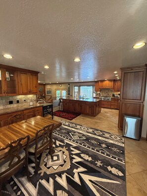 A spacious kitchen with wooden cabinets, a central island, and a patterned rug. - Wasatch Chalet - 3BR Sandy Mountain Retreat (Sandy)