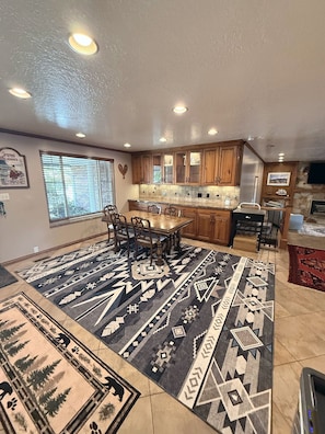 A spacious kitchen with wooden cabinets, a dining table with chairs, and a patterned rug. - Wasatch Chalet - 3BR Sandy Mountain Retreat (Sandy)