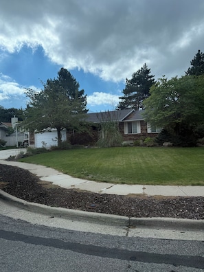 A residential area with a well-maintained lawn, a driveway, and a house with a garage. - Wasatch Chalet - 3BR Sandy Mountain Retreat (Sandy)