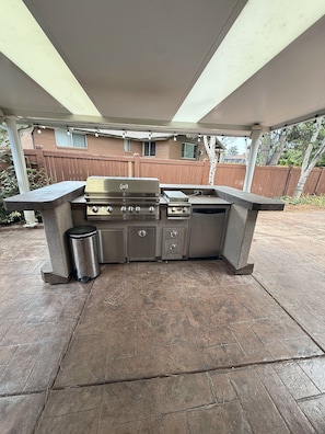 An outdoor kitchen with a grill, sink, and storage cabinets. - Wasatch Chalet - 3BR Sandy Mountain Retreat (Sandy)