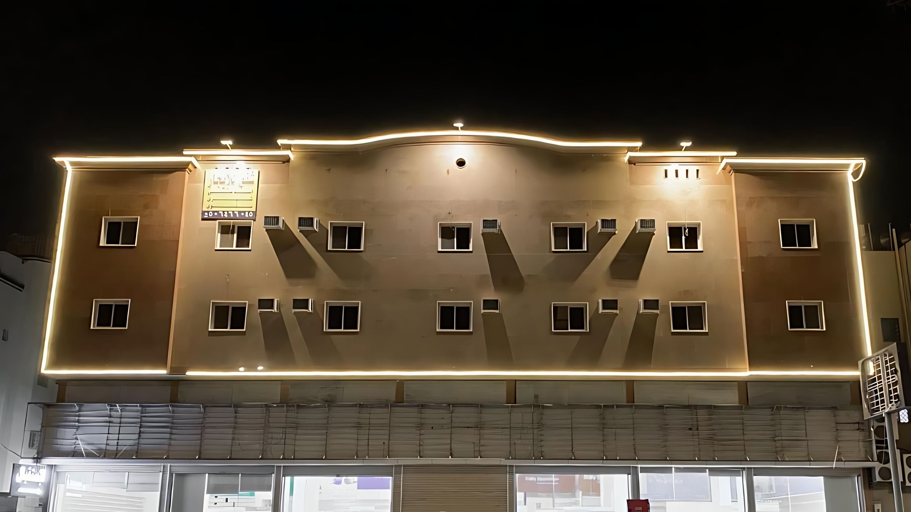 A multi-story building with a flat facade, multiple windows, and a sign above the entrance.