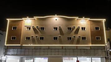 A multi-story building with a flat facade, multiple windows, and a sign above the entrance.