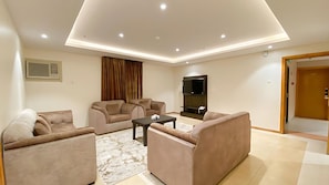 A modern living room with a flat-screen TV, two sofas, a coffee table, and a patterned rug. - REFAD PLUS Ahad rufaidah (Al Khaleej District,Ahad Rafidah)