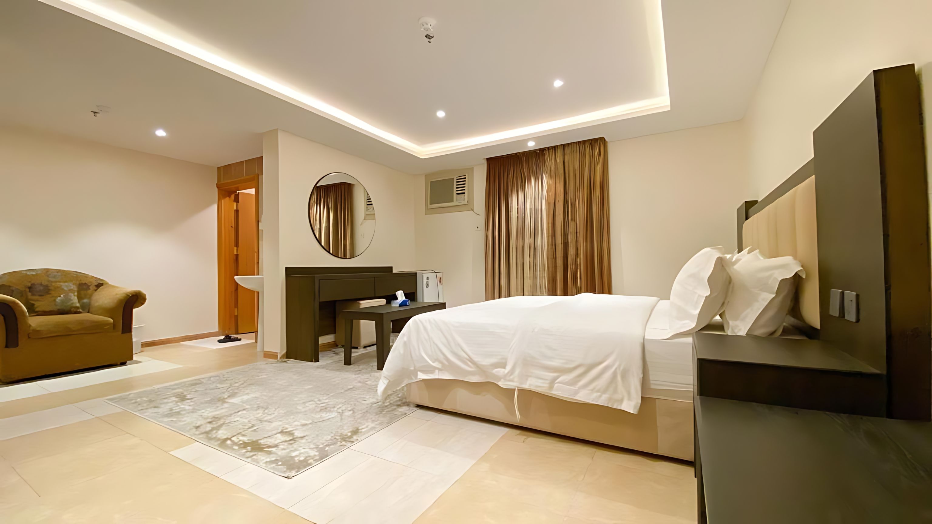 A modern hotel room with a bed, a desk, a chair, and a large mirror.