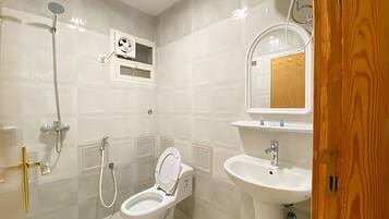 A bathroom with a toilet, sink, and shower.
