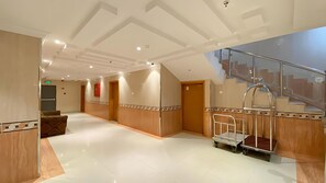 A hotel lobby with a polished floor, a reception desk, a staircase, and a glass railing. - REFAD PLUS Ahad rufaidah (Al Khaleej District,Ahad Rafidah)