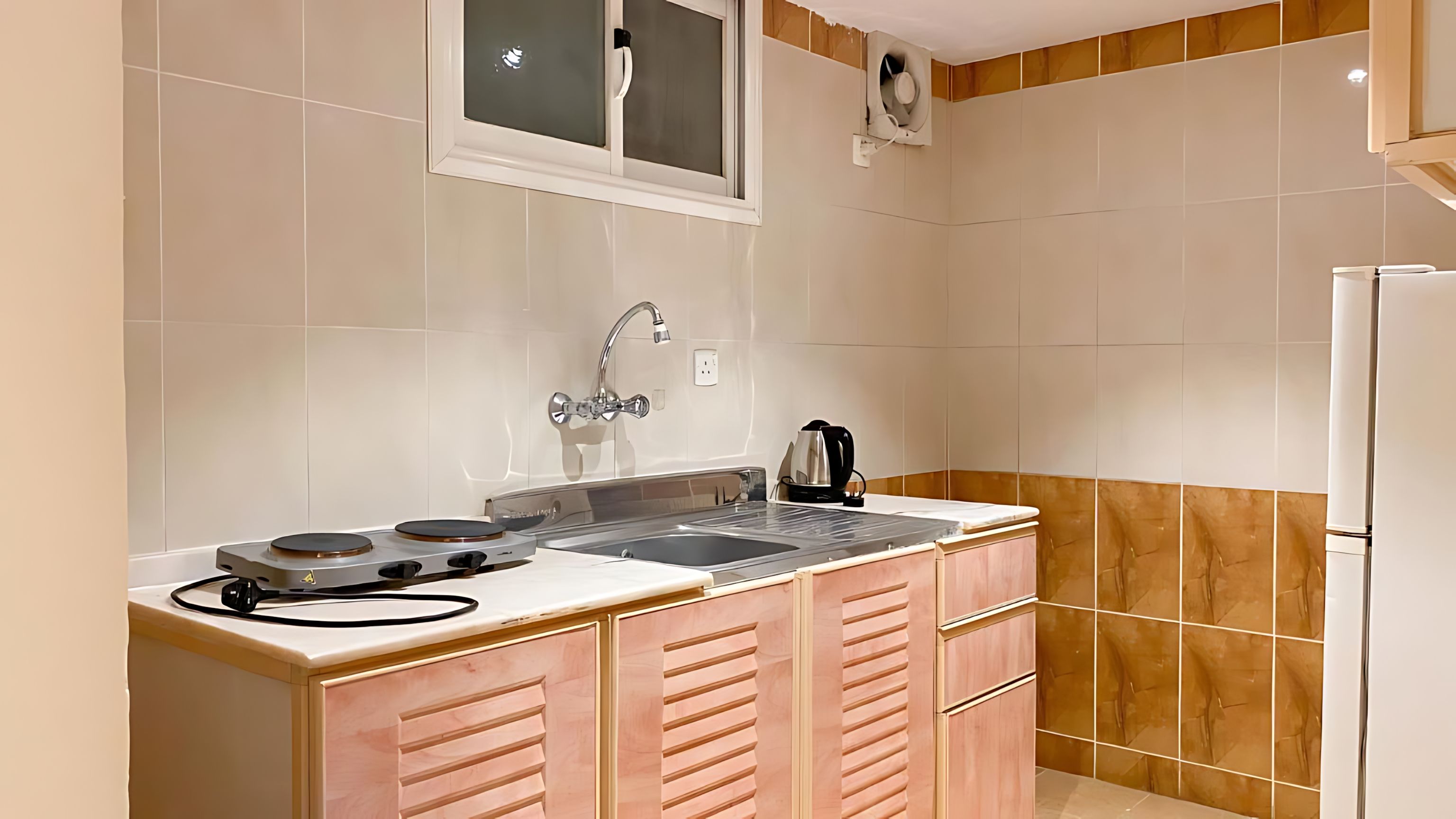 Una cocina compacta con estufa integrada, un lavamanos y armarios de madera.