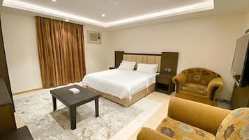 A hotel room with a bed, bedside table, chair, and a television.