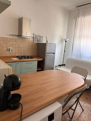 Une cuisine compacte équipée d’une cuisinière à gaz, d’un réfrigérateur et d’un coin repas avec une table et des chaises.