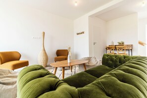 Ein modernes Wohnzimmer mit einem grünen Sofa, einem Holztisch und einem braunen Sessel.
