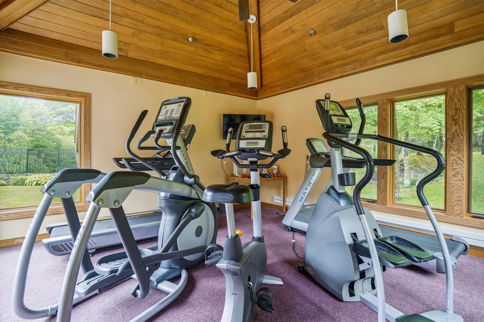 Une salle de sport équipée de trois appareils elliptiques, d’un tapis de course et d’un vélo d’appartement.