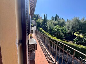 A balcony with a wrought iron railing, a small table, and a view of a garden with trees and a pathway. - SUNSHINE - private parking - 3 min from the historic center - free Wi-Fi (Perugia)