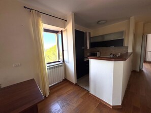 A small kitchen with a window, a microwave, and a wooden countertop. - SUNSHINE - private parking - 3 min from the historic center - free Wi-Fi (Perugia)