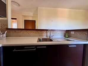 A kitchen with a stainless steel sink, a faucet, and a tiled backsplash. - SUNSHINE - private parking - 3 min from the historic center - free Wi-Fi (Perugia)
