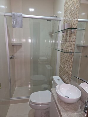 A modern bathroom with a glass-enclosed shower, a toilet, and a sink.