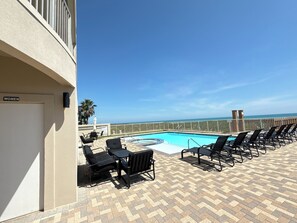 A poolside area with lounge chairs and a sign indicating a women's restroom. - Las Olas 304 -  Exclusive 3br Condo South Padre Island - Steps from the Sand (South Padre Island)