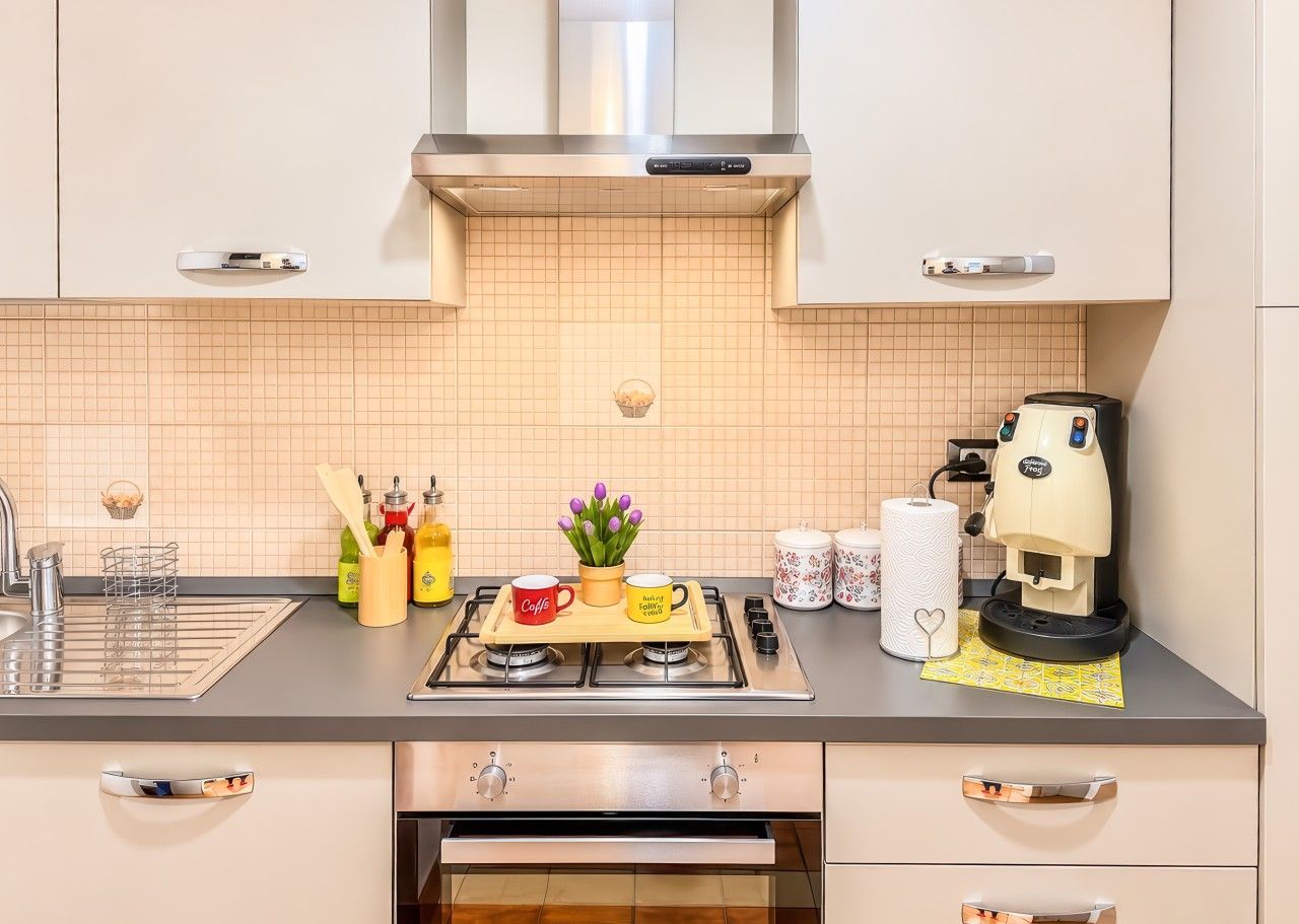 A modern kitchen with a gas stove, a coffee machine, and various kitchen utensils.