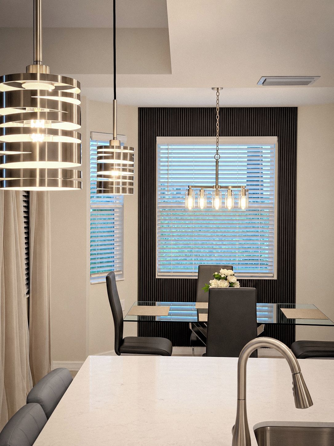 A modern dining area with a glass table, black chairs, and a pendant light fixture.