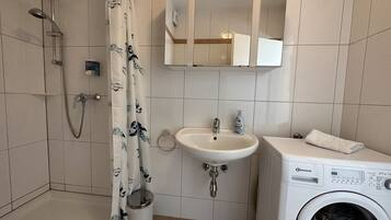 Une salle de bain équipée d’une douche, d’un lavabo, de toilettes et d’un lave-linge.