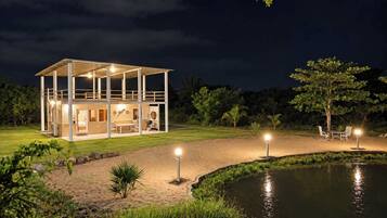 Una casa moderna con un porche cubierto, una piscina y un espacio exterior bien iluminado.
