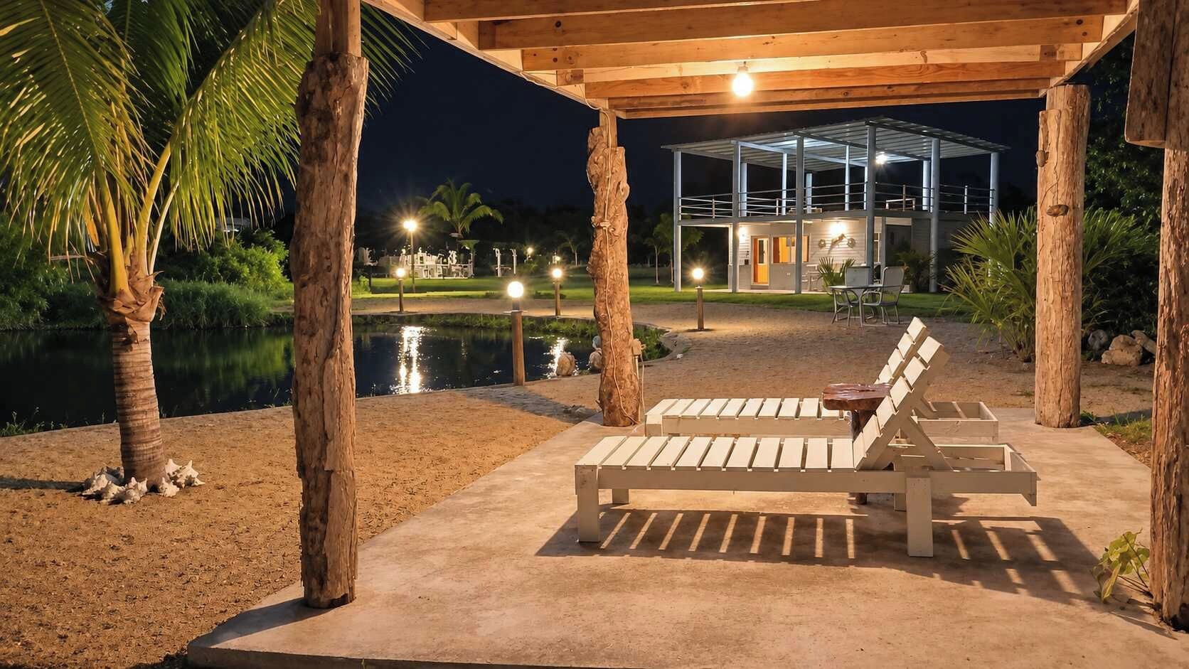 Un'area salotto esterna coperta con poltrone, una piscina e un edificio sullo sfondo.