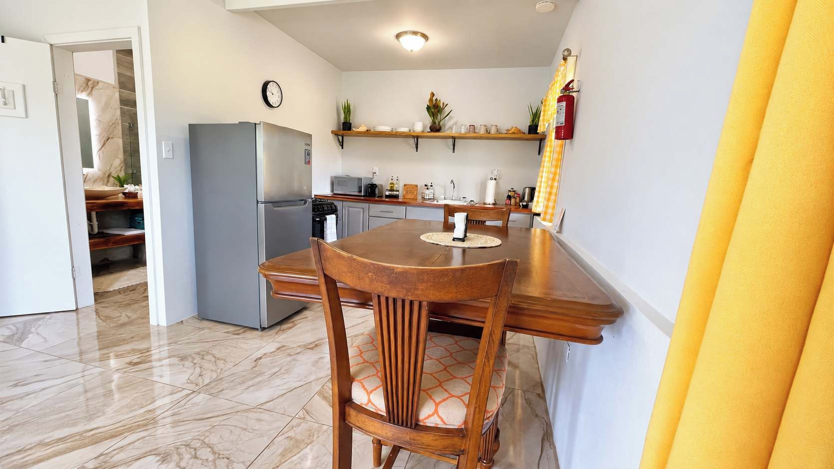 A compact kitchen with a refrigerator, microwave, and wooden dining table.