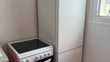 A compact kitchen with a built-in stove, oven, and a refrigerator.