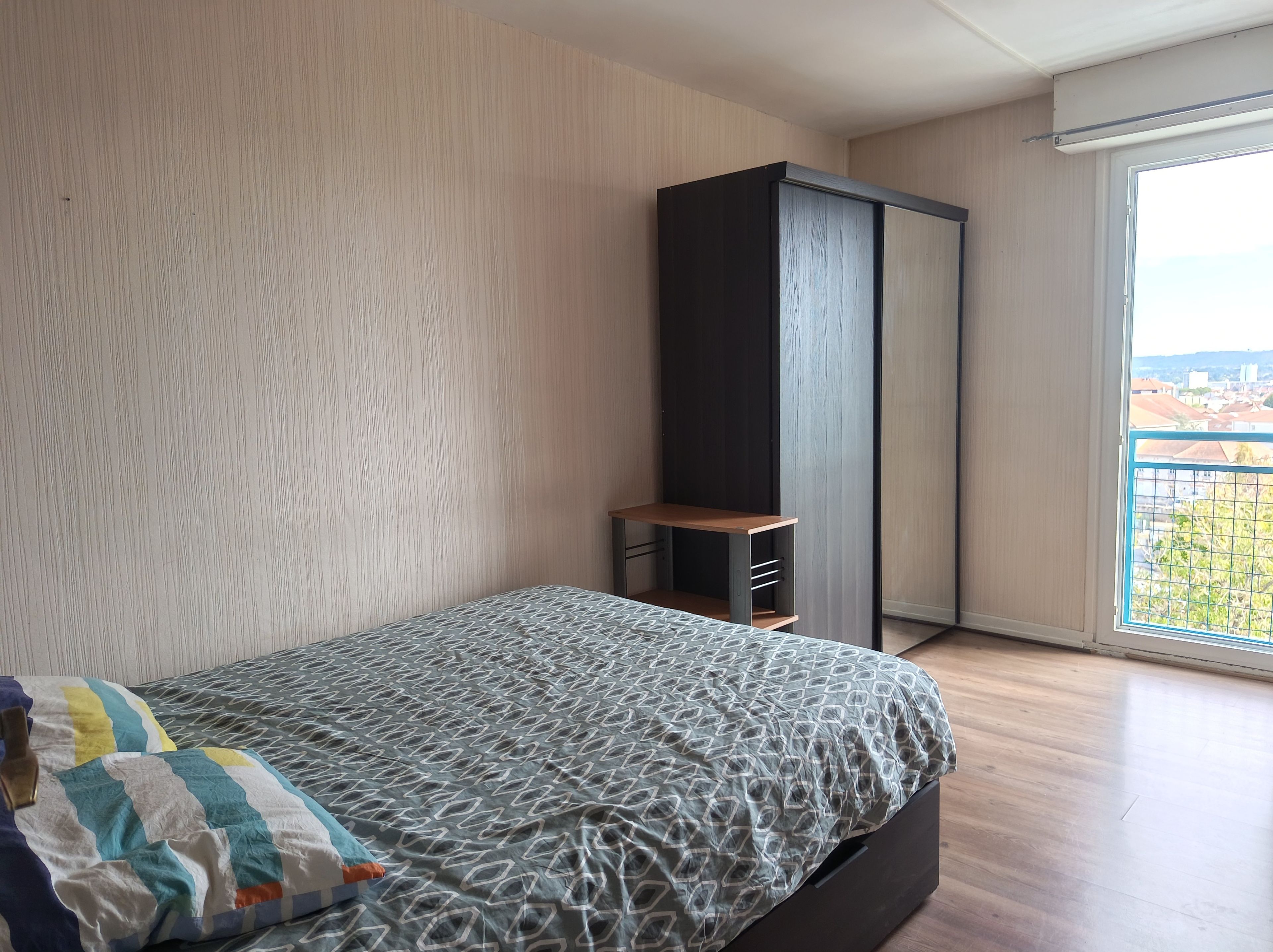 Une chambre à coucher avec un lit, une armoire et une fenêtre donnant sur un beau paysage.