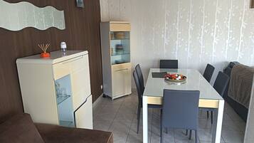 Ett kompakt bostadsutrymme med en matplats, ett litet kök och en soffa.