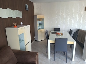 Een ruimtelijke leefruimte met een eethoek, kitchenette en een bank.