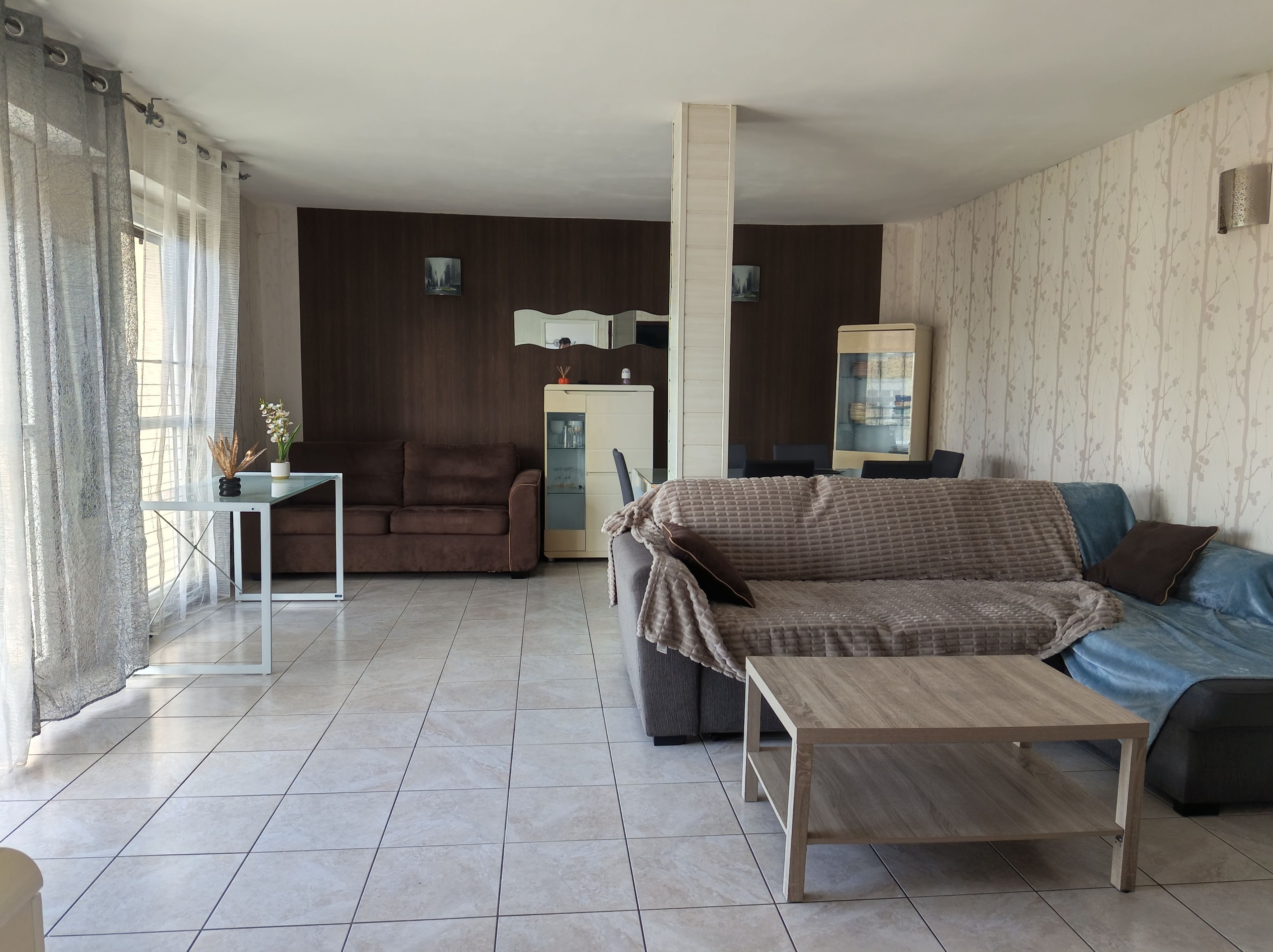 Ein Wohnzimmer mit einer Couch, einem Couchtisch, einem Esstisch und einem Schrank.