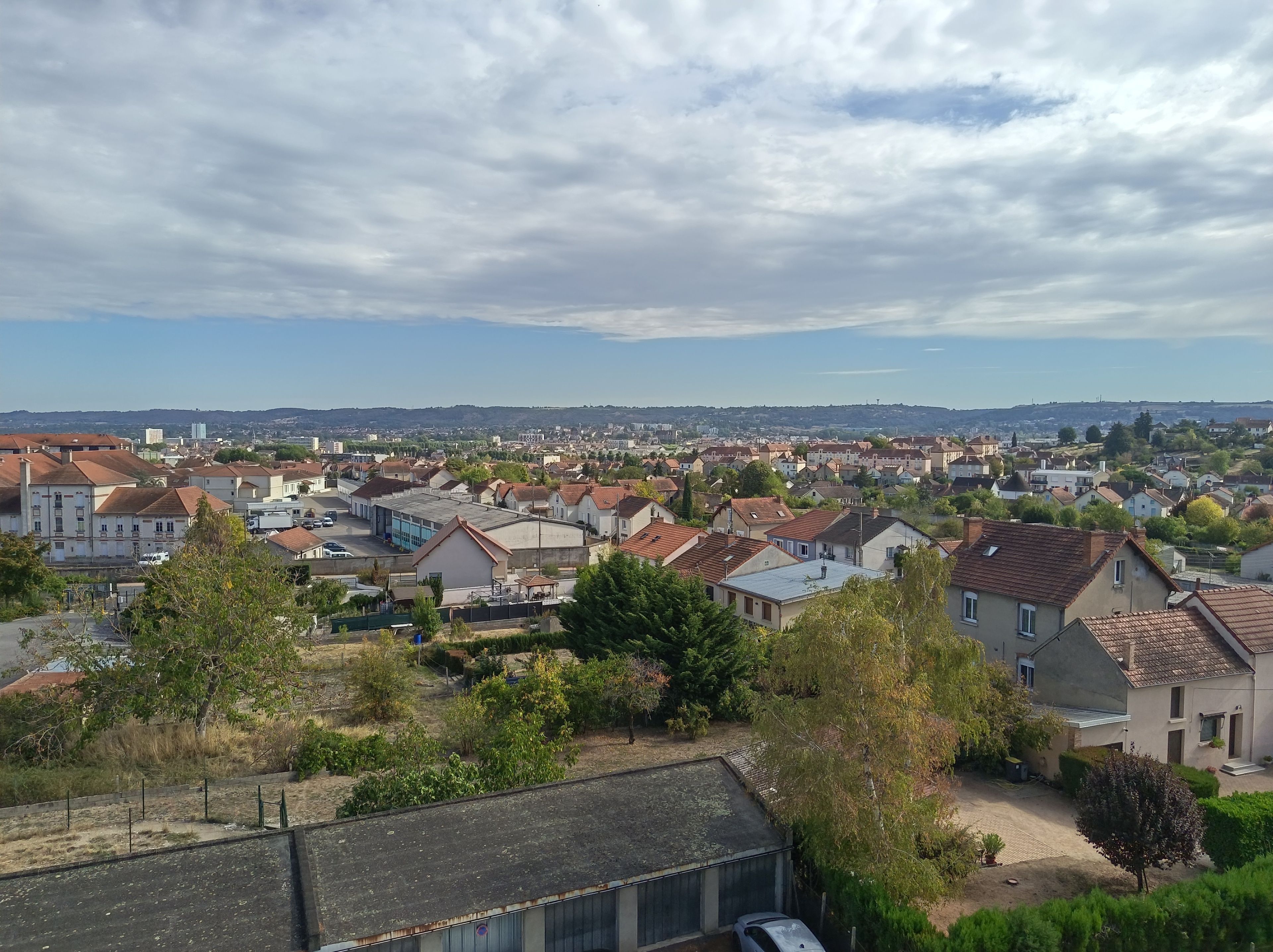 Área residencial com casas, árvores e céu claro.