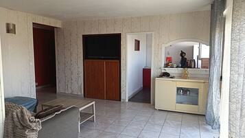 A living room with a sofa, a TV, a cabinet, and a red door.